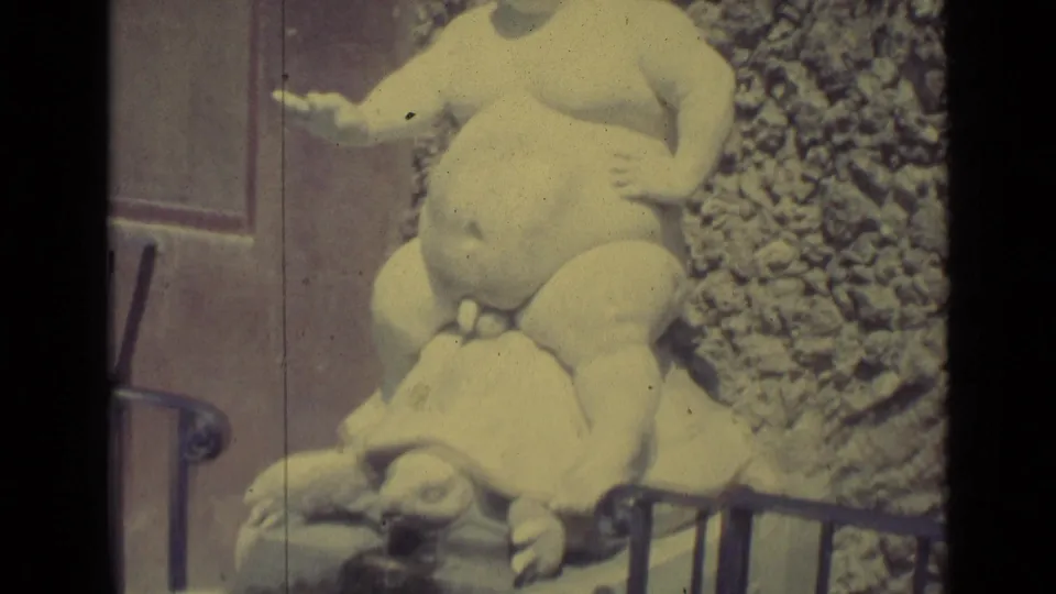 Close 1962 Florence frame of the pale stone boy-on-turtle sculpture, cropped tightly against rough masonry and railing.