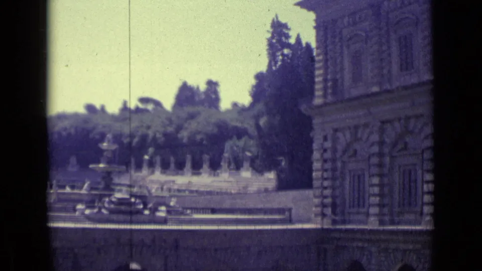 1962 Florence travel frame showing a palace edge, fountain basin, garden statuary, and tree-lined grounds.