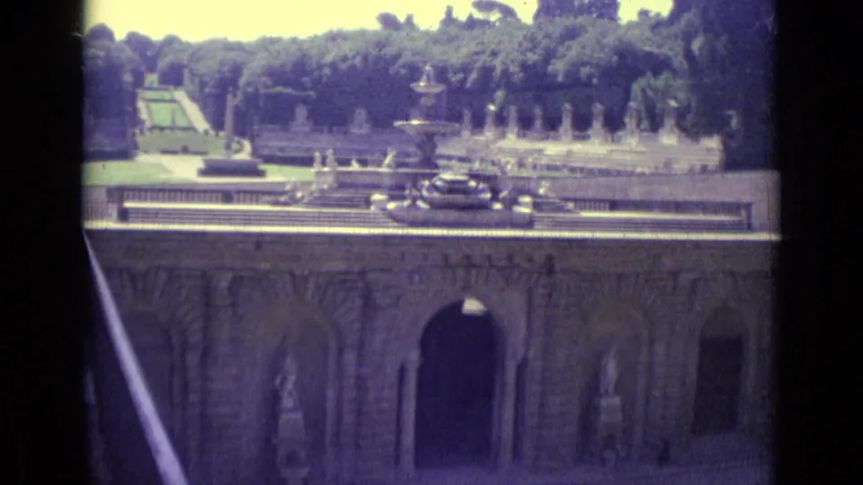 Florence 1962 travel footage frame showing the fountain garden, statues, dense trees, and arched stone architecture.
