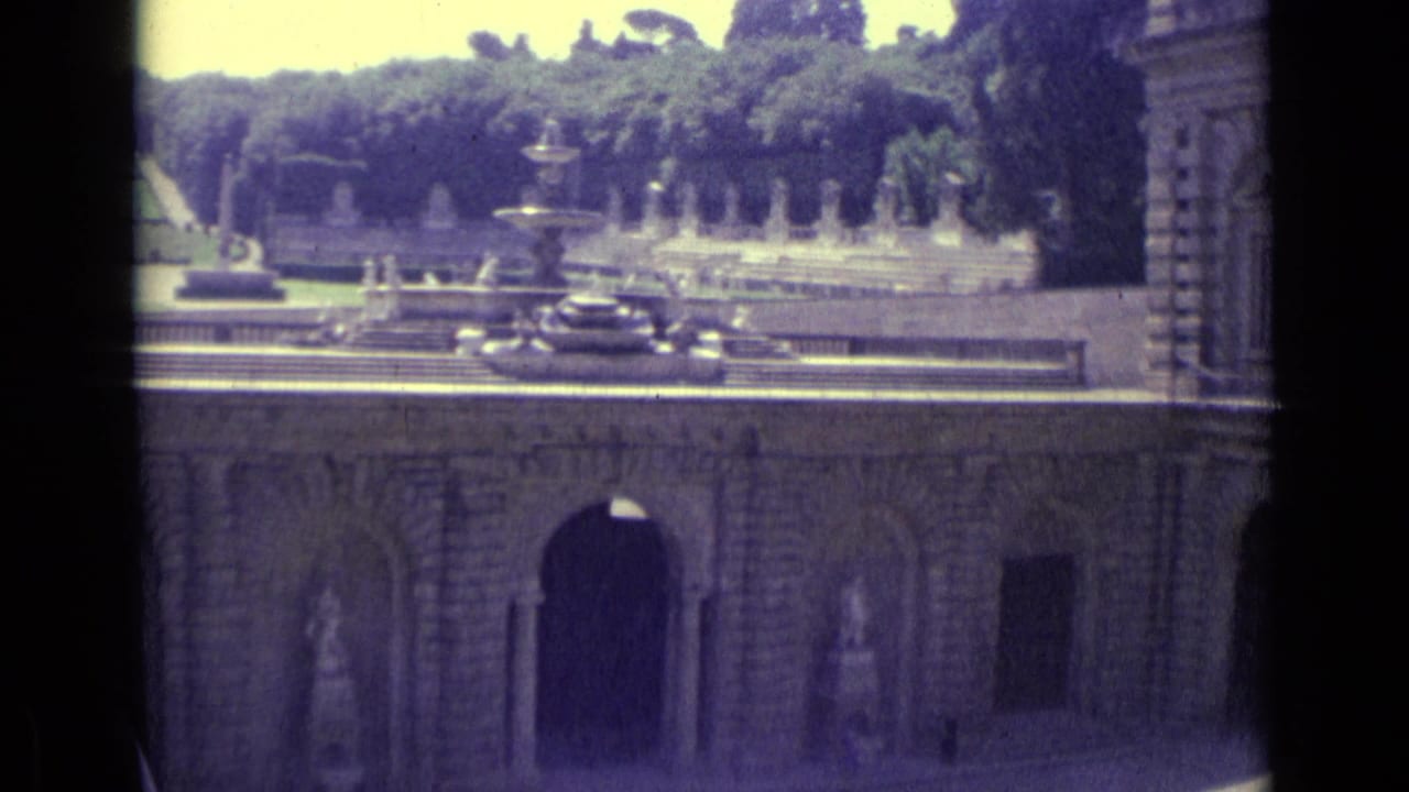 1962 8mm Florence travel frame showing a stone courtyard, arched openings, a fountain, statues, and trees beyond.