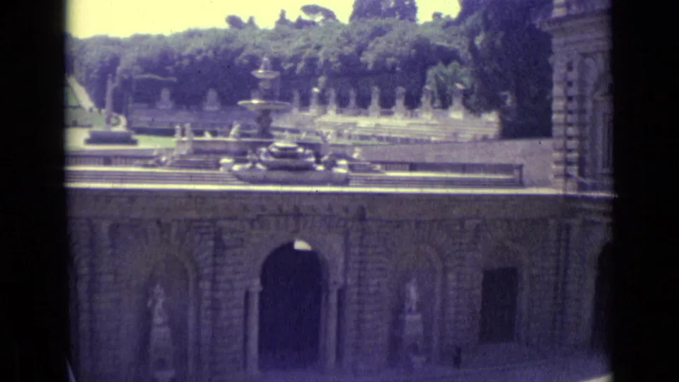 1962 8mm Florence travel frame showing a stone courtyard, arched openings, a fountain, statues, and trees beyond.