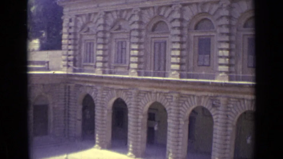 Final 1962 Florence frame showing a long stone facade with repeated arches, shuttered upper windows, and shadowed arcade openings.