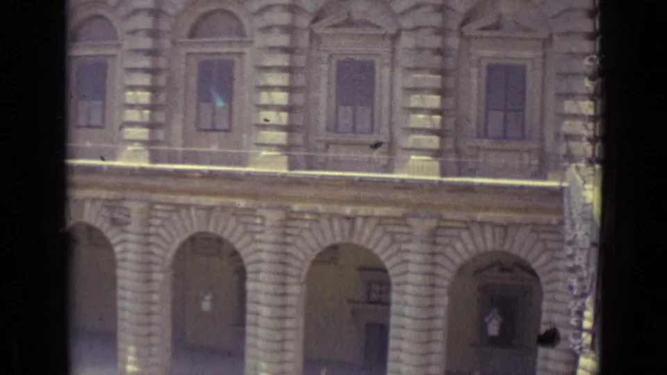 A closer 1962 travel-film view shows shuttered upper windows, heavy stone detailing, and arched ground-floor openings on a Florence facade.