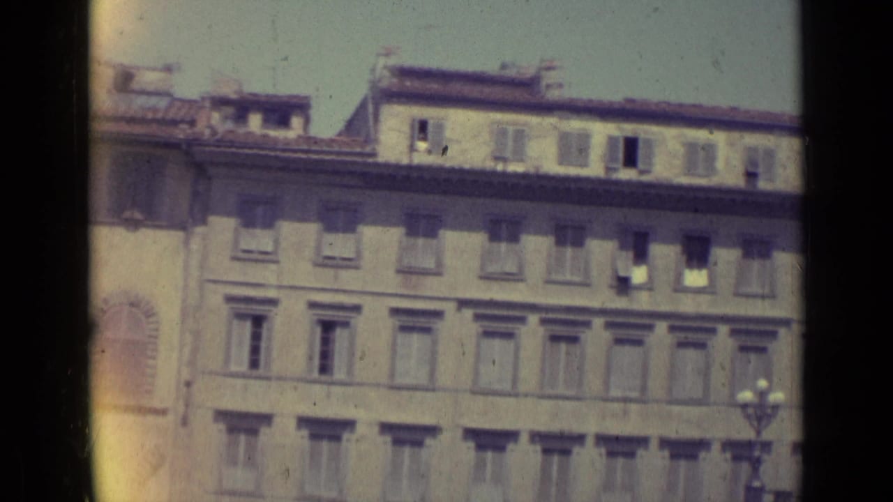 Long building facade with rows of shuttered windows and roofline details.
