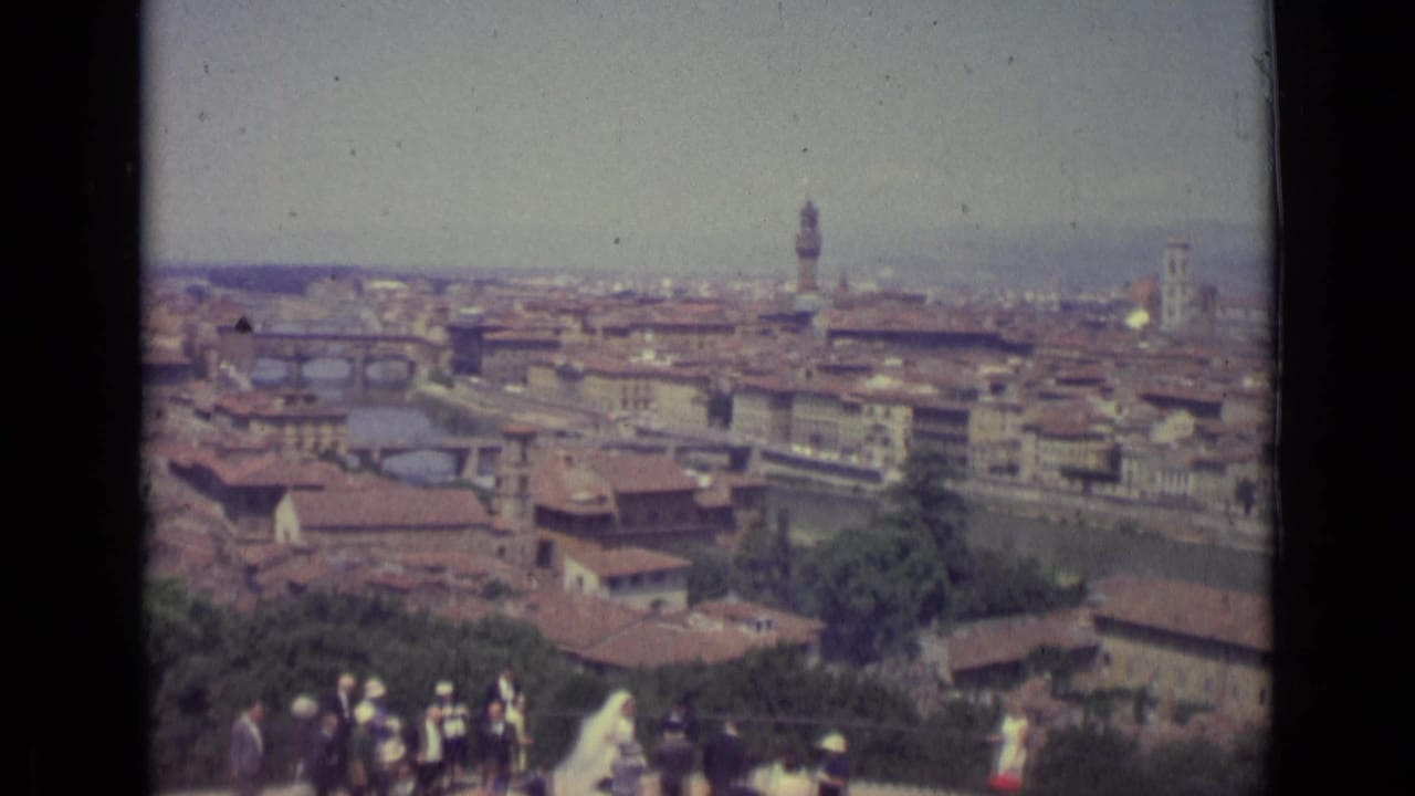 1962 8mm view over Florence, Italy, showing the Arno River, historic rooftops, Palazzo Vecchio tower, and wedding guests in the foreground.