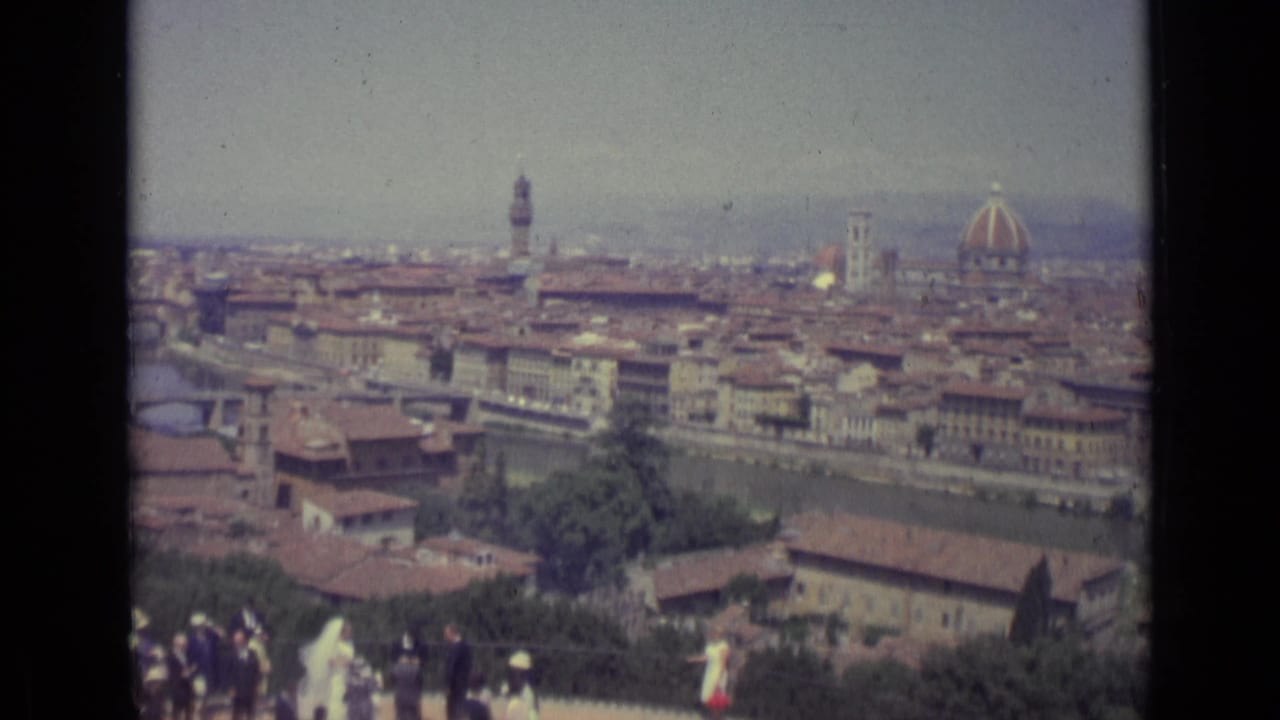 Florence panorama with the Duomo dome, riverfront buildings, and wedding guests at the lower edge.