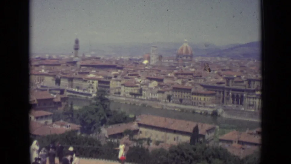 Faded 8mm Florence view from 1962, with the Duomo dome and Arno River beyond a partially visible wedding party on the terrace.