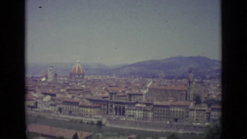 1962 home-movie view over Florence with the Duomo at left, riverfront buildings below, compact rooftops, hills, and visible 8mm frame edges.