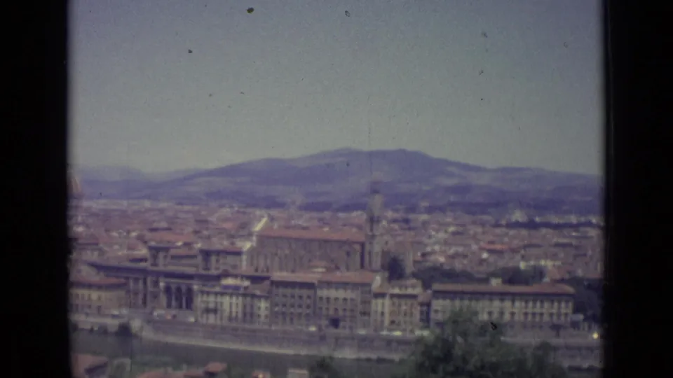 Late frame from the 1962 Florence view, showing the Arno riverfront, historic rooftops, a tower, distant hills, and part of the Duomo at the left edge.