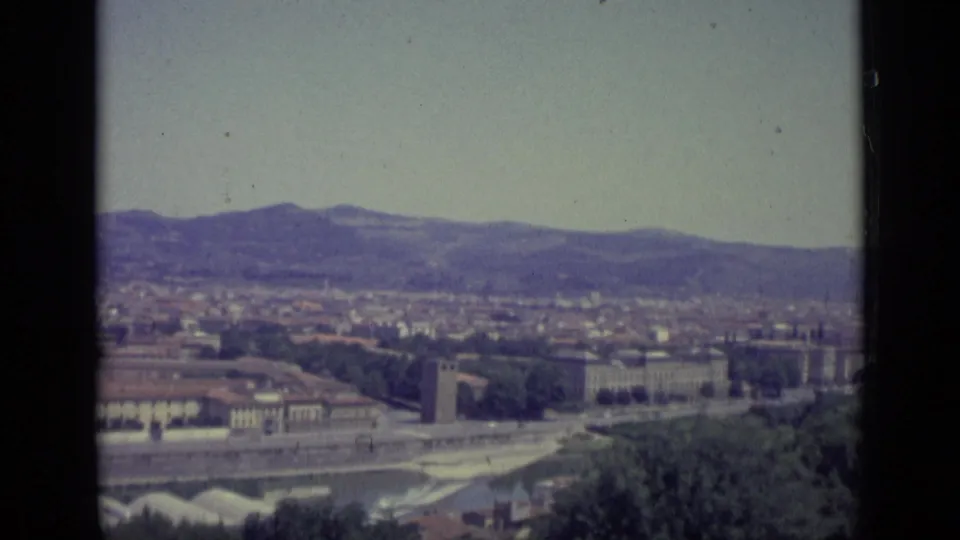 1962 8mm panorama continues across Florence, with the Arno River below, urban blocks, foreground greenery, distant hills, and visible film edges.