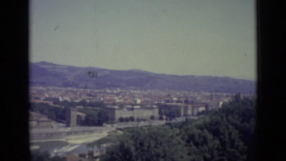 Final 1962 Florence frame shows the river corridor, foreground trees, low city buildings, distant hills, and soft faded color from the 8mm scan.