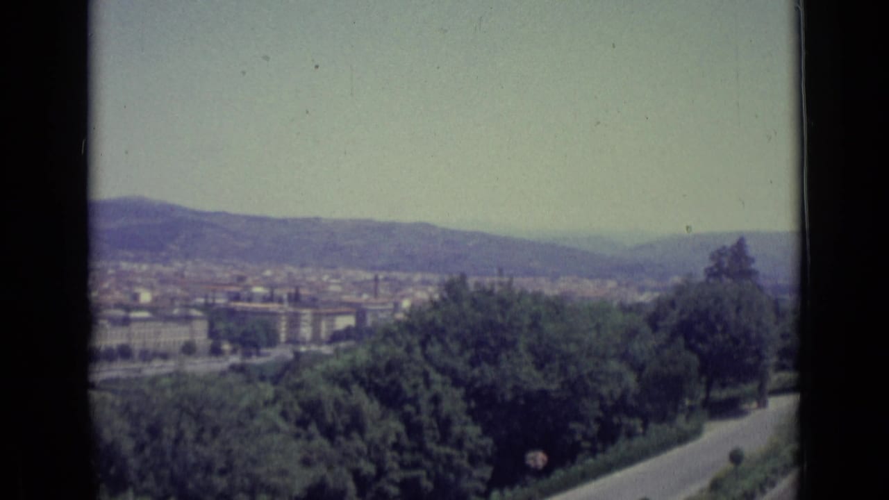 Florence cityscape and surrounding hills remain visible as the handheld camera pans toward trees and the overlook road.