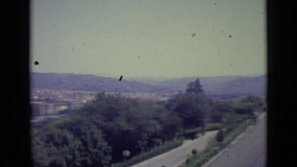 From the Florence overlook, the frame shows a curving road, dark trees, distant buildings, and hazy hills on 8mm film.