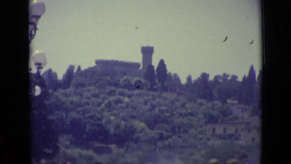 Distant Florence hillside with a fortress-like tower, trees, and soft color fading from 8mm film.