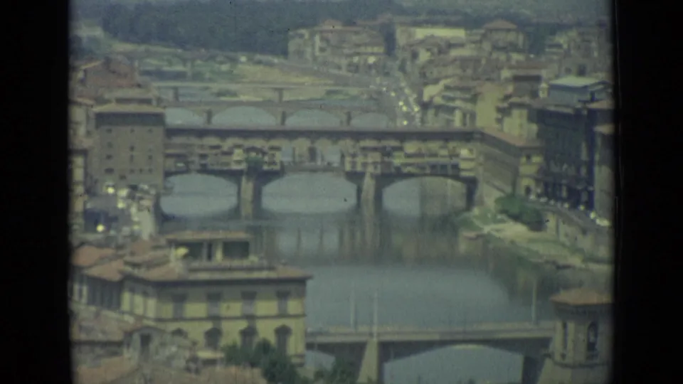 1962 Florence river view with a historic stone bridge crossing the Arno and buildings lining the banks.