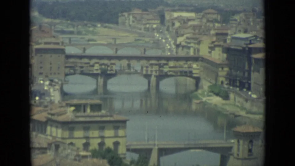 1962 8mm elevated view over Florence showing the Arno River, Ponte Vecchio, nearby bridges, rooftops, and distant hills.