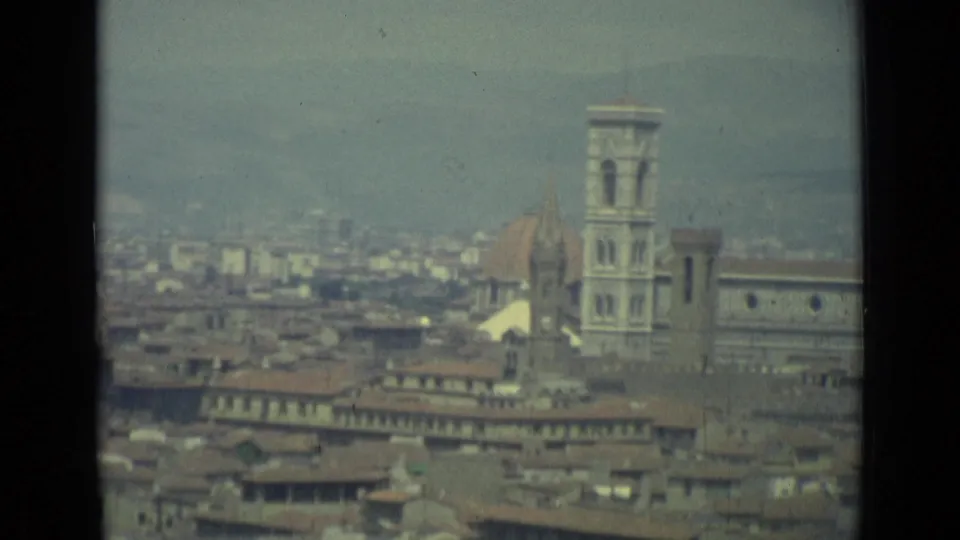 1962 8mm elevated view across Florence toward the cathedral dome and bell tower, with dense rooftops in the foreground.