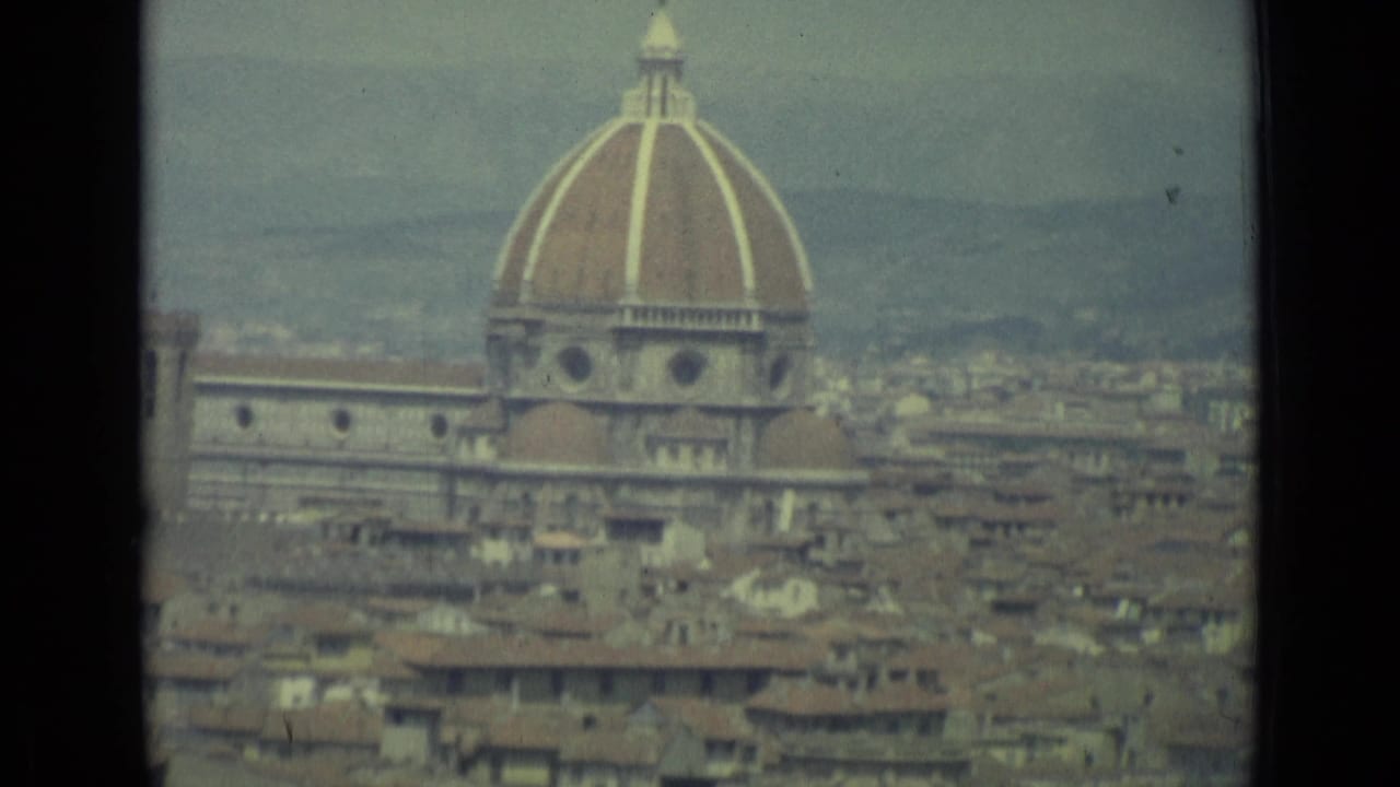 1962 8mm view of Florence showing the cathedral dome, surrounding rooftops, and distant hills under a hazy sky.