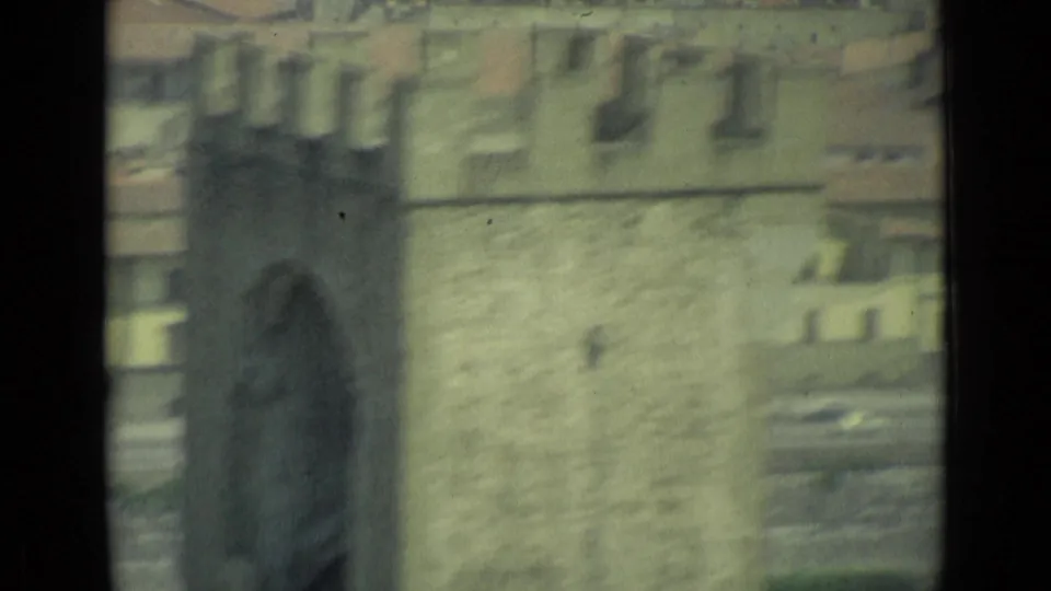 Soft-focused 8mm frame from Florence with stone building walls, tiled rooftops, and dark frame borders visible.