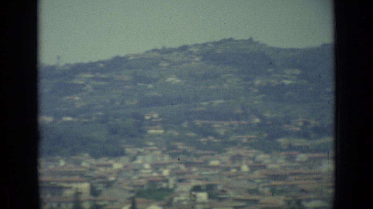 A muted 8mm view of Florence and surrounding hills, partly obscured by a dark vertical border in the frame.