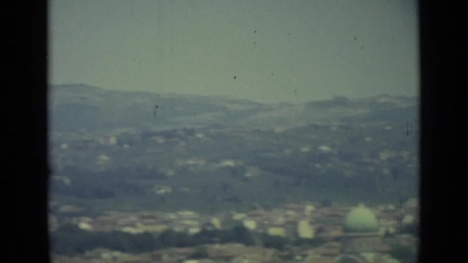 Distant 1962 Florence panorama showing rooftops, surrounding hills, and a pale green dome through soft 8mm focus.