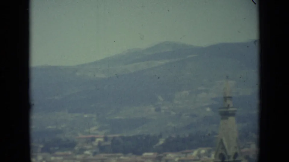 1962 8mm view over Florence with hazy hills, rooftops and a tower-like structure near the center of the frame.