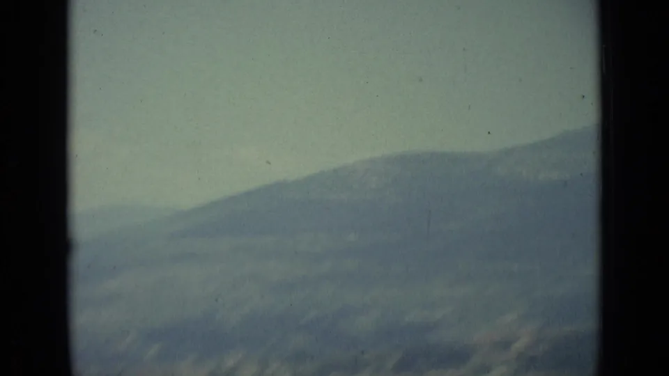 Soft 8mm frame showing distant hills or mountains above Florence under a pale, hazy sky.