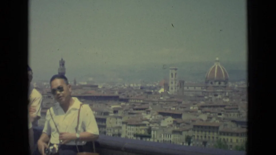 1962 Florence overlook with an adult tourist in sunglasses near the railing and the Duomo dome visible in the background.
