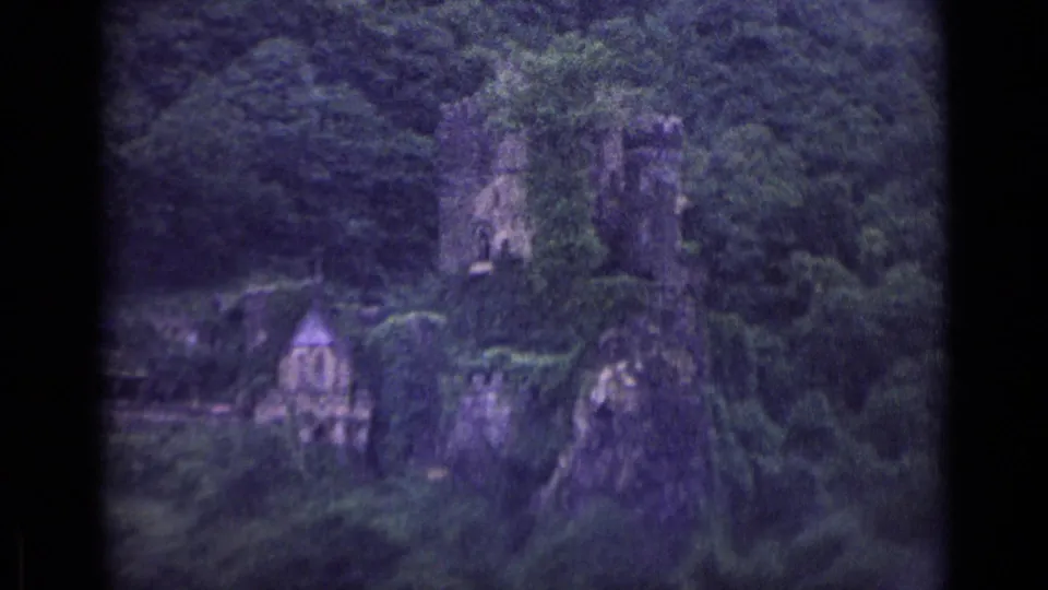 1962 German 8mm travel frame showing stone ruins and a small chapel-like structure set into a wooded cliffside.