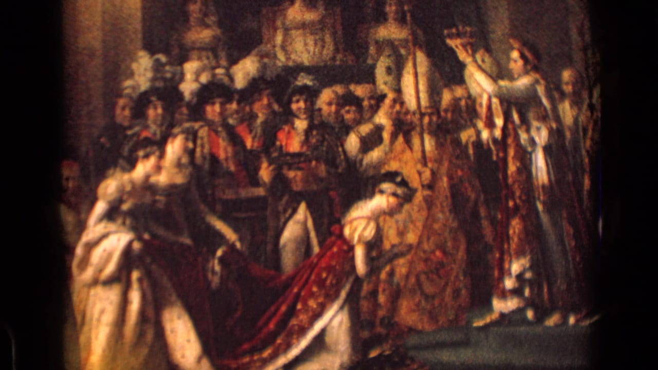 1962 Germany home-movie frame of a coronation artwork or display, with a central crown gesture, clustered figures, and a kneeling woman.