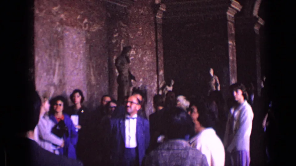 A wider 1962 8mm view shows adults in mid-century clothing gathered in a museum hall with sculptures and dark archways.