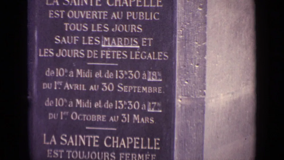 Close 8mm view of a French sign for La Sainte Chapelle, with public hours and closure details visible.