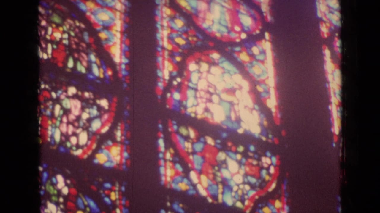 Close view of stained-glass panels with oval figure scenes.
