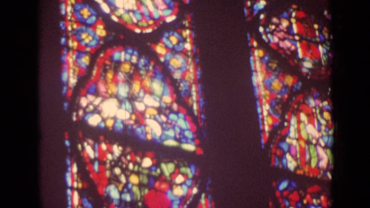 Colorful stained glass panels beside a dark vertical interior structure.