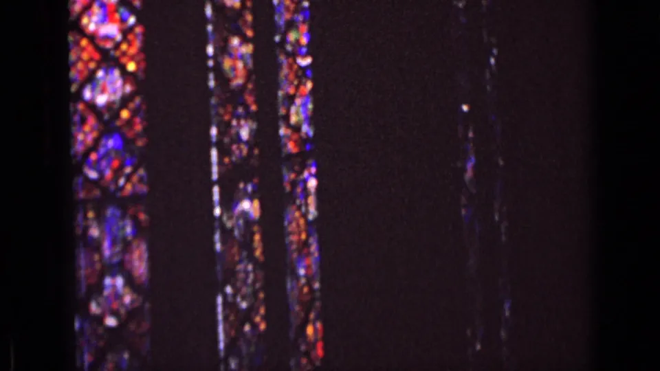 The 1962 Germany home-movie frame shows stained glass windows glowing in red, blue, and purple against a dark interior.