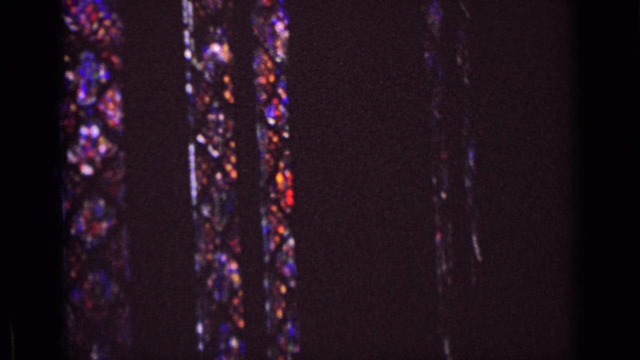 1962 Germany 8mm frame showing a dim church interior with vertical stained glass panels and saturated color from the windows.
