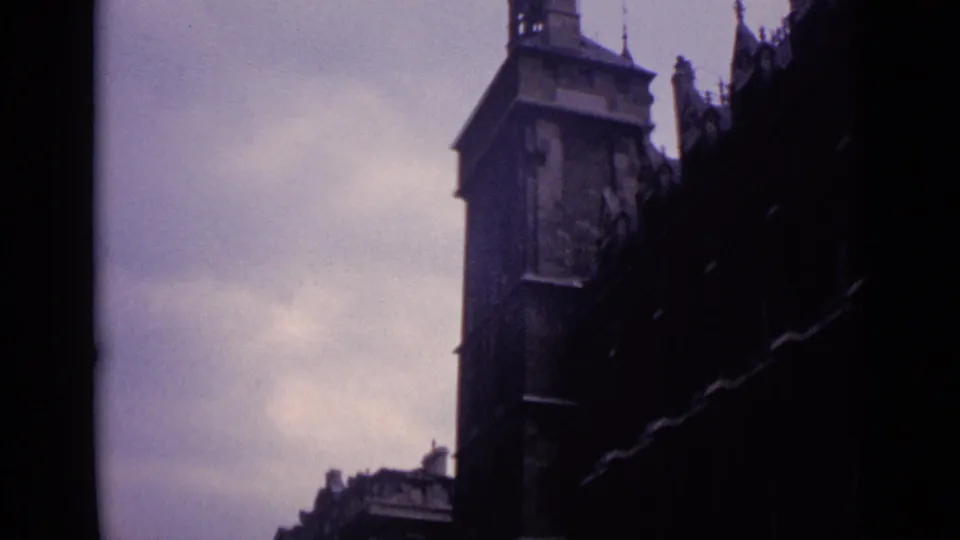 1962 Germany home-movie frame with a church bell tower and adjacent historic roofline in soft 8mm color.