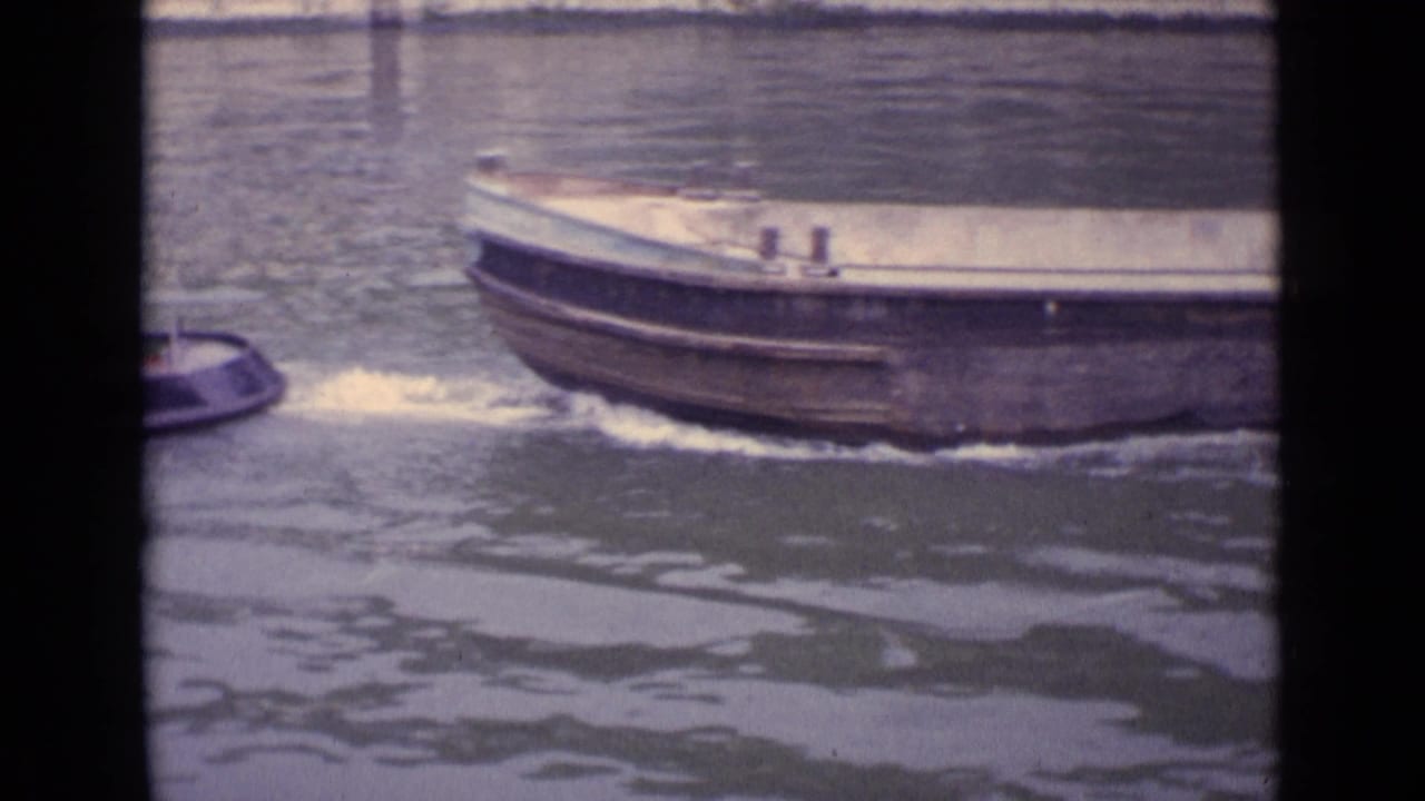 Barge bow and partial tugboat moving across rippled river water.