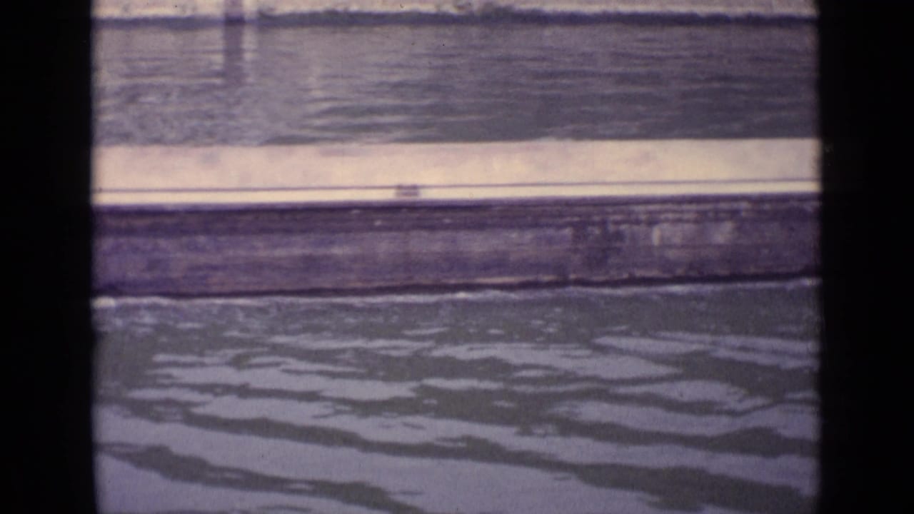 Water surface with a shoreline or embankment seen through the 8mm frame edge.