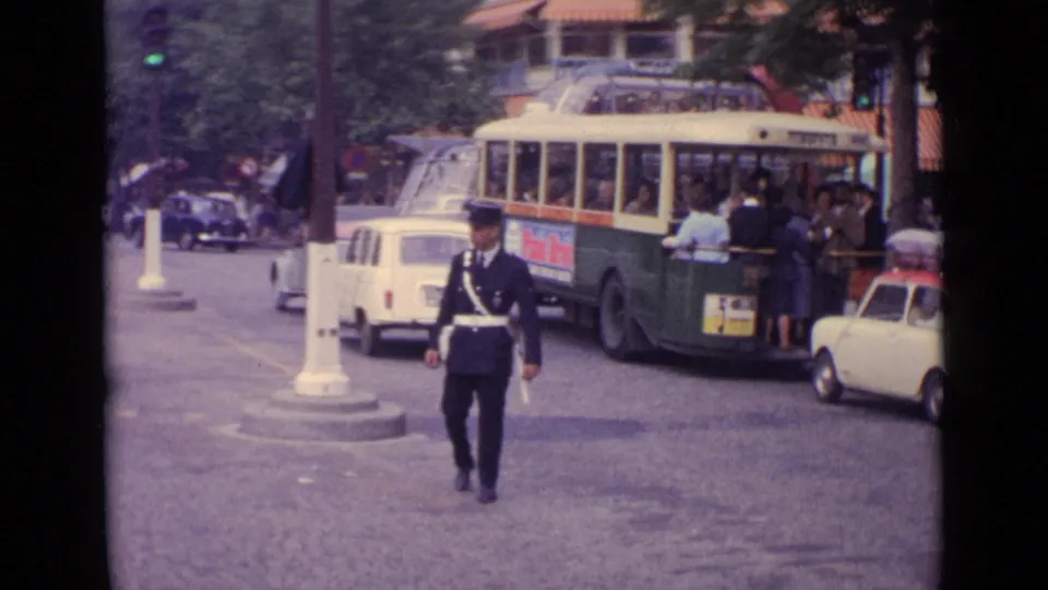 1962 Germany frame showing a traffic officer walking across the intersection before a trolleybus and waiting pedestrians.