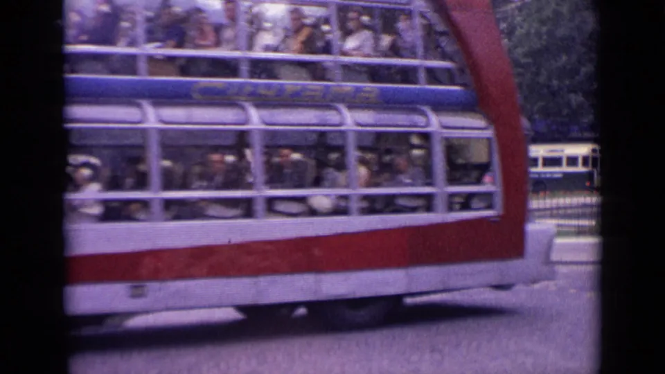 Close 8mm view of a large double-decker bus in Germany, with many passengers visible through its long windows.