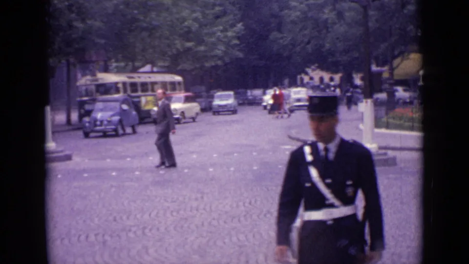 A uniformed traffic officer stands near the camera while 1962 Germany street traffic continues behind him.