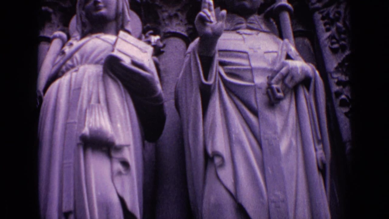 Close view of robed stone religious figures holding a book and staff-like objects.