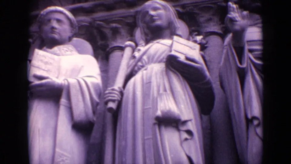 1962 Germany close-up of sacred stone figures on a church facade, with robed figures, headwear, a book, and carved architectural recesses.