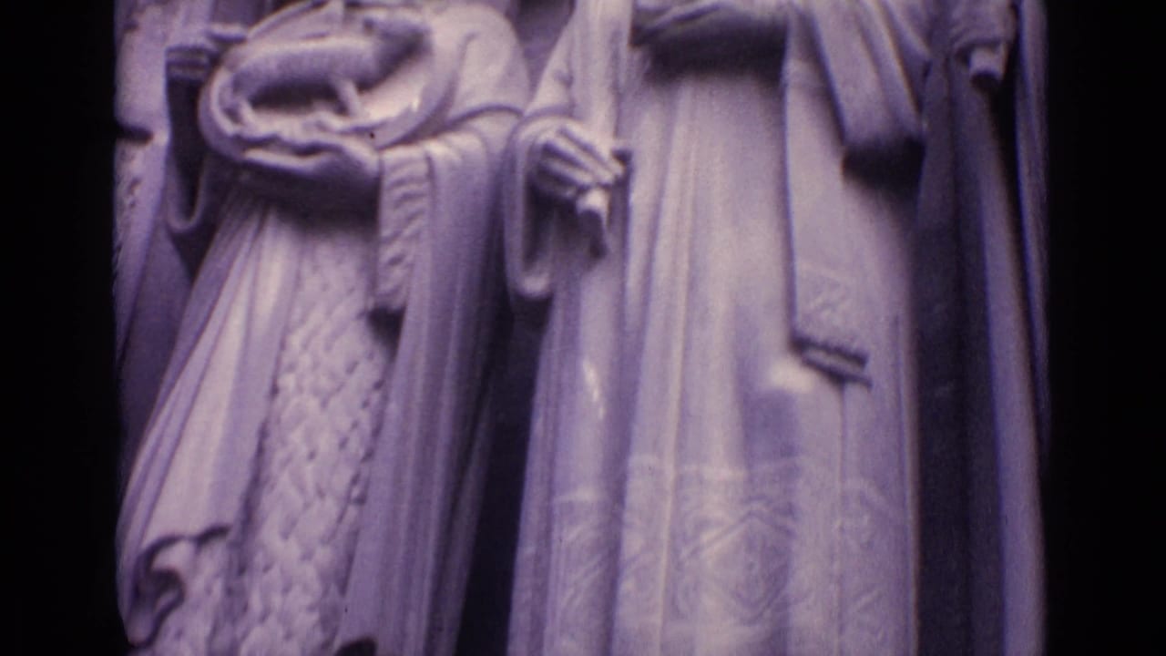 1962 Germany 8mm frame showing robed stone figures on a historic building, including one figure holding a cross-like object.