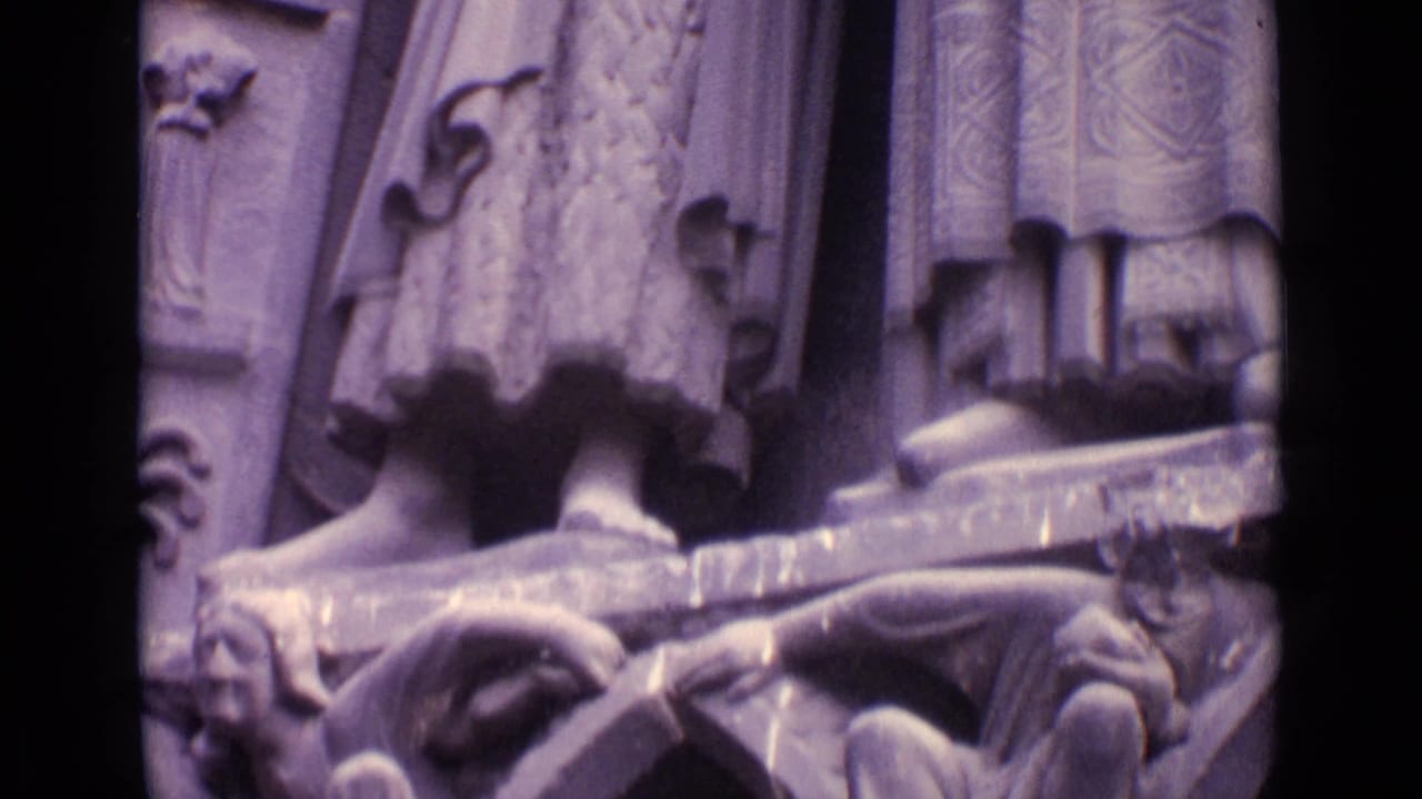 1962 Germany 8mm frame with lower portions of carved figures, decorative stone supports, and grotesque architectural sculpture.