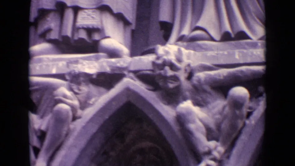 1962 Germany 8mm frame showing pointed Gothic-style arches, grotesque stone figures, and the lower drapery of statues above.