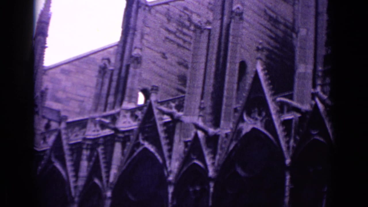 Purple-tinted 8mm frame of Gothic cathedral gables and pointed arches.