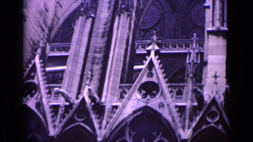 1962 Germany 8mm frame of a Gothic cathedral exterior, showing arched windows, tracery, and weathered stone details.