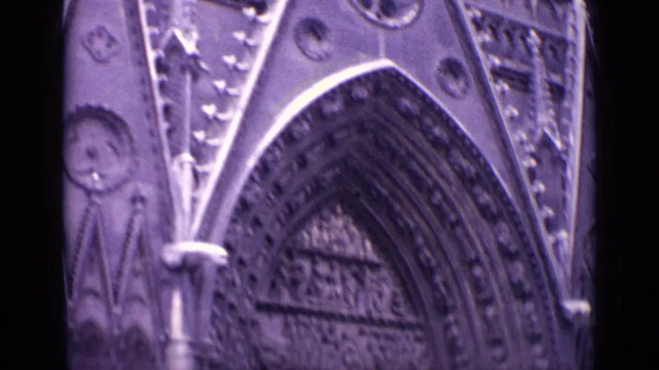 1962 Germany frame focusing on a pointed Gothic-style arch, layered stone molding, carved tympanum area, and adjacent facade decoration.